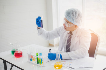 Fototapeta premium Scientists or researchers look at multicolor test tubes in science labs. Science, chemistry, biology concept.