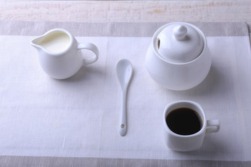 Cup of hot coffee espresso, coffee beans, jug of milk, and bowl with sugar on white background for copy space. Coffee concept.
