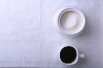 Cup of hot coffee espresso, coffee beans, jug of milk, and bowl with sugar on white background for copy space. Coffee concept.