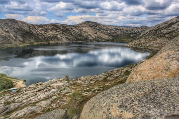 Naklejka premium Mountain lake, clouds reflected in its waters. Stone mountains. Natural landscape. Sibinskie lakes. Eastern Kazakhstan.