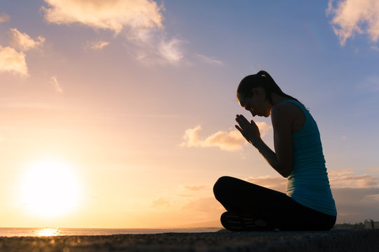 Young woman silhouette praying.