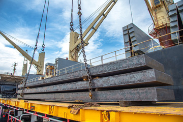 bundle of steel slabs being loading discharging in port terminal, laying onto base of trailer,...