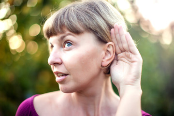 Listening.Close up on hand woman and ear listening for a quiet sound or paying attention outdoor