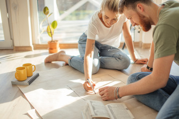 Portrait of happy caucsian couple planning new house design looking at paper - obrazy, fototapety, plakaty