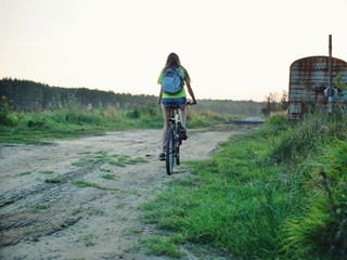 Fototapeta premium Polonne / Ukraine - 14 September 2018: girl in a green T-shirt with a backpack riding a bike