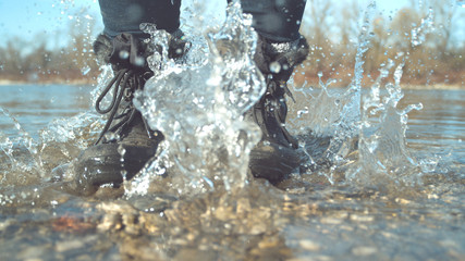 CLOSE UP: Unrecognizable playful woman jumping in shallow water of a stream.