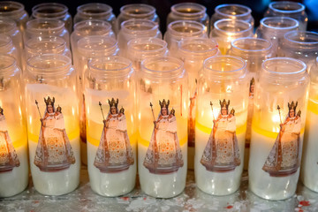Closeup of votive prayer candles in glass containers with painted designs. Selective focus