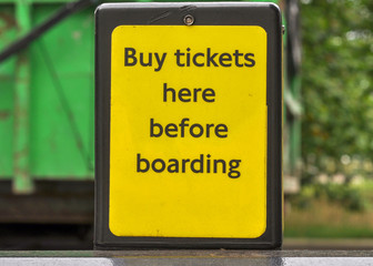 A sign at the bus stop with the inscription "Buy tickets here before boarding"