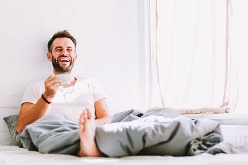 Young man drinking coffee in bed