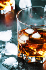 Bourbon with ice in glass on gray bar counter, selective focus