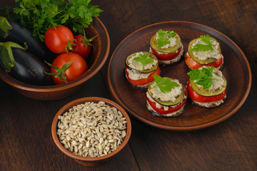 A dish of raw eggplant and tomato slices, a sauce made from sunflower seeds