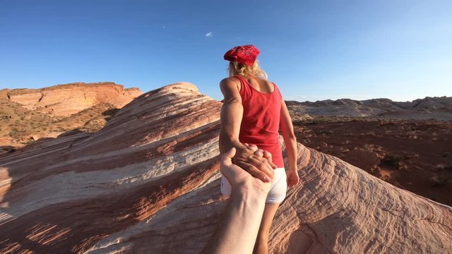 Follow me, sporty girl holding hands at top of Fire Wave Trail. Young caucasian woman in Valley of Fire State Park, Nevada, USA. Concept of the journey of woman tourist traveler, holding man by hand.