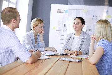 Young people studying with books on desk. Beautiful women and men working together.