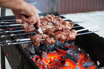 In the summer barbecue is cooked on the grill. Meat on skewers. The smoke from coals.