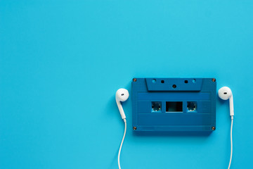 Retro cassette tape with earphones on blue background for music and relaxation concept