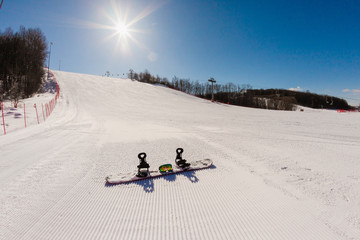 Bottom view on empty ski slope and equipment for snowboarding
