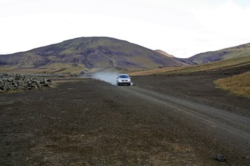 Coche circulando por las solitarias pistas del desierto volcánico de Islandia (Iceland).