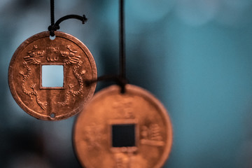 Oriental, magical pendants. Traditional asiatic and chinese currency, transformed into fortune coins with powerful engravings. Bronze, copper, gold necklace, black thread, blurry background.   - obrazy, fototapety, plakaty