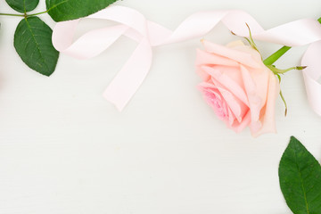 Rose fresh flower with ribbon on table from above with copy space, flat lay scene
