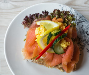 Sandwich with smoked salmon and fresh vegetables, in natural light. Concept for healthy nutrition.