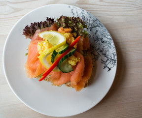 Sandwich with smoked salmon and fresh vegetables, in natural light. Concept for healthy nutrition.