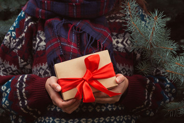female hands with gift box with red bow