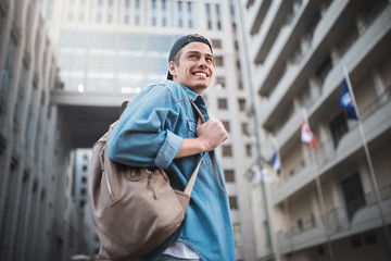 Cheerful young man with backpack enjoying walk the city