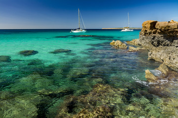 Two sailboats and rocky coast