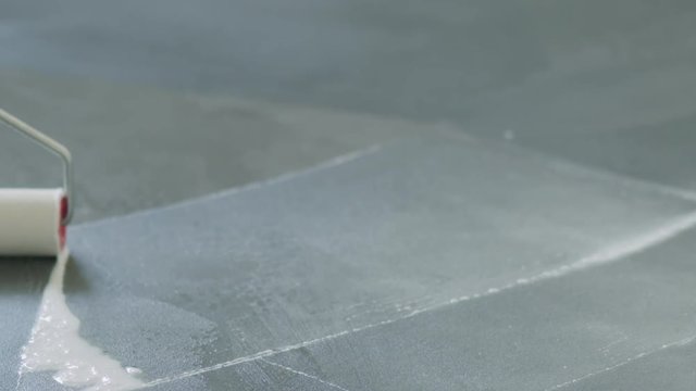 Slow motion closeup pan applying sealant on the concrete floor