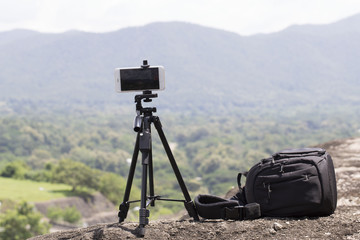 Smartphone on tripod taking a photo  at the mountains. Blurry background.