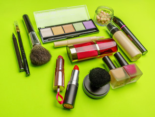 The composition of accessories, makeup cosmetics on a bright green background. Top view.   