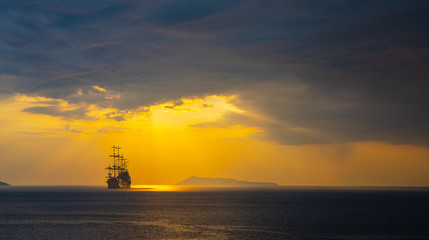 Pirate ship at the open sea at the sunset