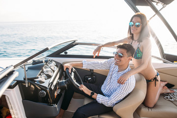 Newly married caucasian couple driving sailboat, enjoying water summer adventure, spending...