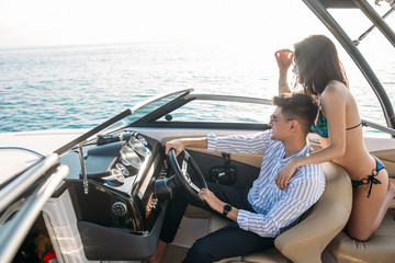 Young married couple having sea excursion on motor boat while spending their honeymoon trip on...