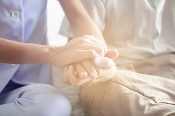 Fototapeta na wymiar Comforting hand. Young nurse holding old man's hand.