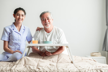 Young attractive nurse and senior man in bed portrait.