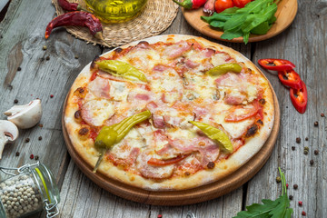 Pizza with tomatoes, mozzarella cheese, black olives and basil. Delicious italian pizza on wooden pizza board.