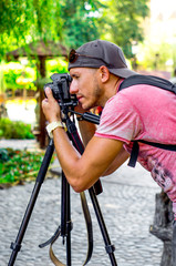 young male photographer photographing nature in the Park on a black camera on a tripod