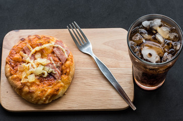 Pizza hawaiian on wood dish with cool cola.
