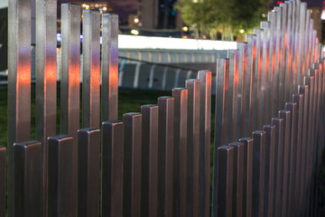 The wavy wood fence near the road in the colours of car traffic lights 