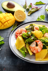 Fresh Shrimps, Avocado, Mango salad with lettuce green mix, herbs, lemon, healthy food.