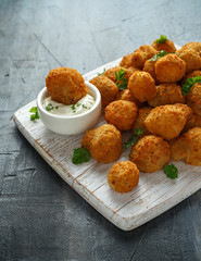 Homemade Breaded Garlic Mushrooms with sour cream and parsley on white wooden board