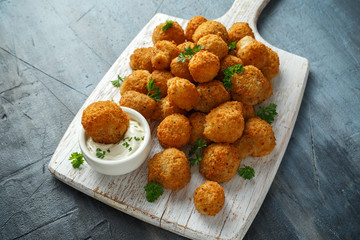 Homemade Breaded Garlic Mushrooms with sour cream and parsley on white wooden board