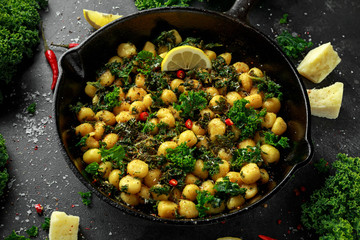 Fried kale and potato gnocci with chilie, peccorino cheese and lemon wedges in rustic pan. Italian food