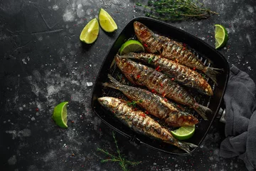 Foto auf Acrylglas Fertige gerichte Grilled sardines with thyme, chili and lime wedges on cast iron skillet