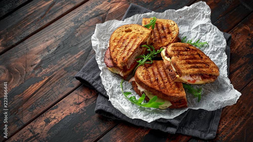 Wall mural grilled sandwich with turkey, bacon, tomato and cheese on rustic wooden background