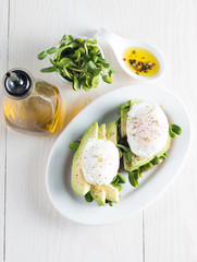 Avocado toast, cherry tomato on wooden background. Breakfast with toast avocado, vegetarian food, healthy diet concept. Healthy sandwich with avocado and poached eggs.