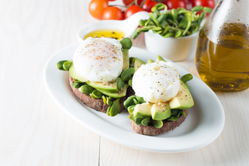 Avocado toast, cherry tomato on wooden background. Breakfast with toast avocado, vegetarian food, healthy diet concept. Healthy sandwich with avocado and poached eggs.