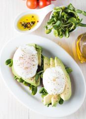 Avocado toast, cherry tomato on wooden background. Breakfast with toast avocado, vegetarian food, healthy diet concept. Healthy sandwich with avocado and poached eggs.