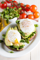 Avocado toast, cherry tomato on wooden background. Breakfast with toast avocado, vegetarian food, healthy diet concept. Healthy sandwich with avocado and poached eggs.